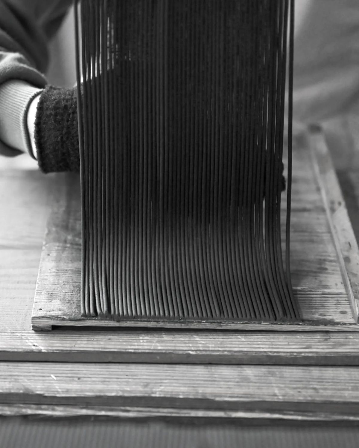 Freshly extruded incense sticks being laid out by hand on a drying board