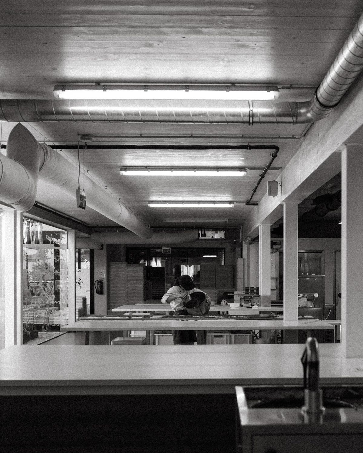 A maker at work across an empty workshop floor